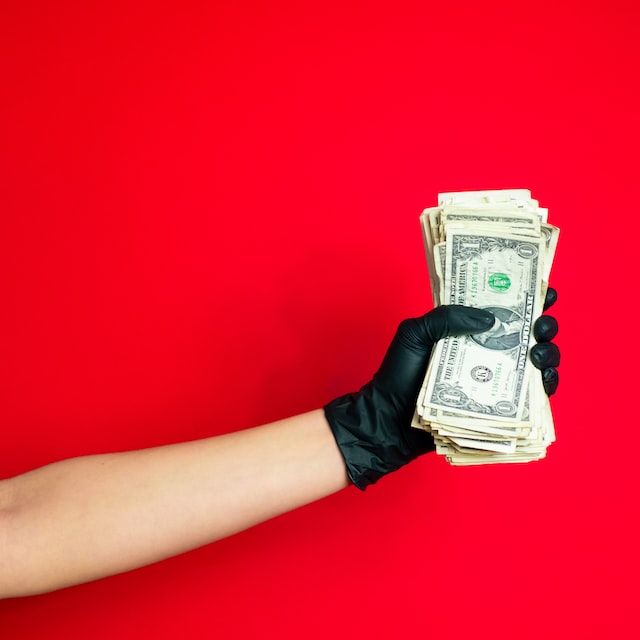 dłoń w rękawiczce trzymająca pieniądze